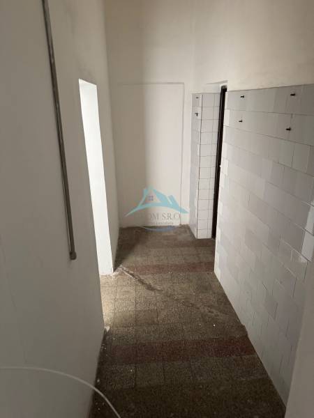 A narrow interior with tiled flooring and a paneled wall in commercial premises.