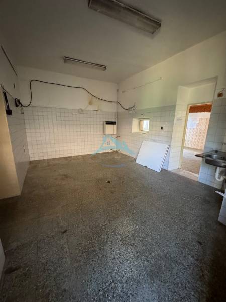 Interior of commercial premises with older tiles and flooring, empty room with a sink.