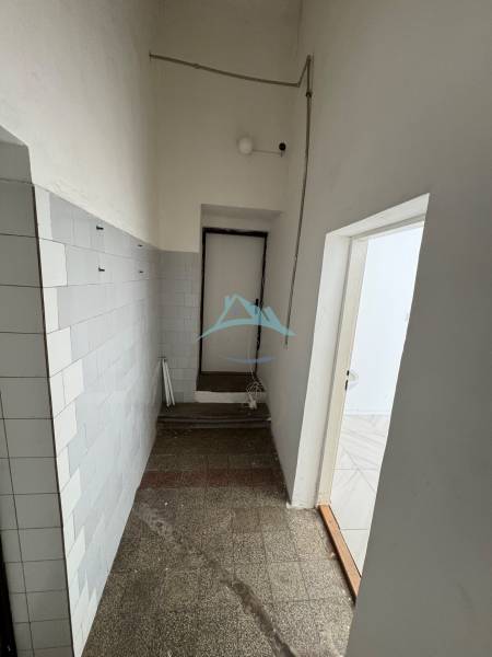 A narrow corridor with tiled walls and light in commercial premises.