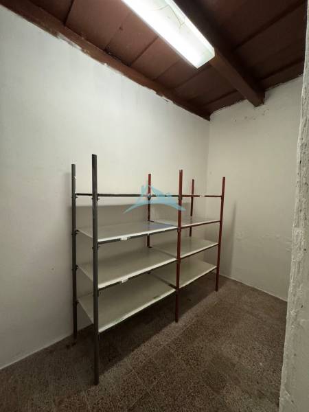 A storage room in commercial premises with a metal shelf and ceiling lighting.