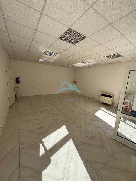 An empty commercial space with ceramic tiles and a plasterboard ceiling.