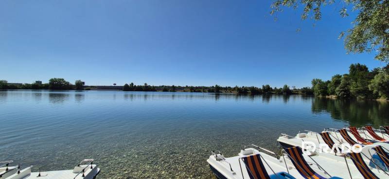 A lake with pedal boats in Bratislava - Vajnory, surrounded by greenery and a clear sky.