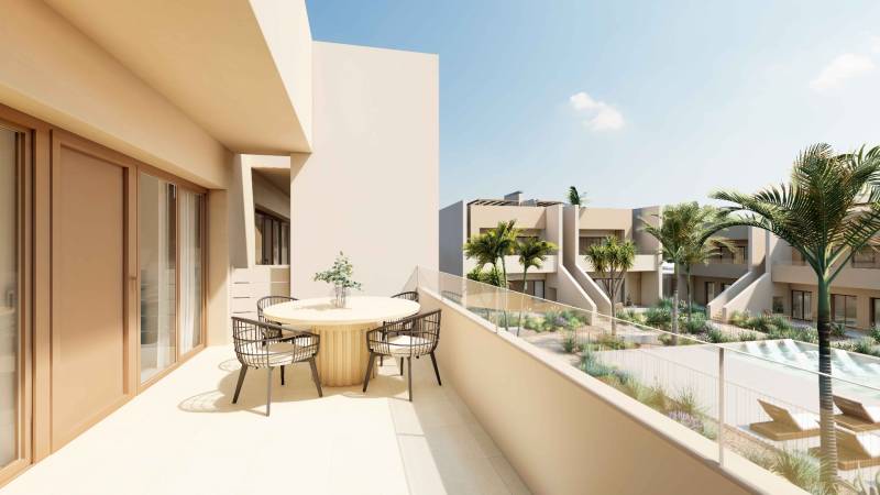 A balcony with a table and chairs in a 4-room apartment overlooking greenery and a pool.