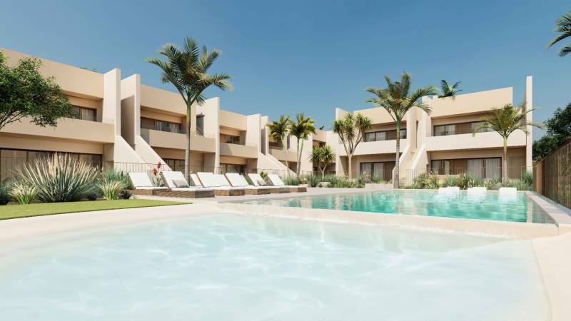 Pool and loungers in the complex of 4-bedroom apartments in the town of Roda with palm trees.