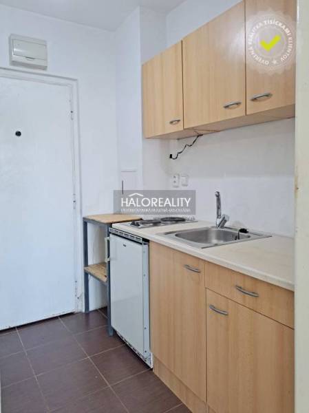 A kitchenette in a studio apartment with wooden furniture and a white sink.