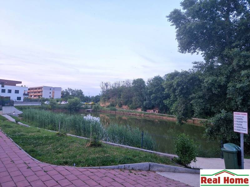 Lake with a path in Senec, Vtáčia Street, between trees and residential buildings.