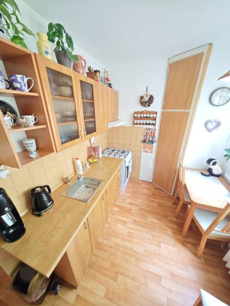 A kitchen in a 2-room apartment with wooden furniture, a dining corner, and decorations.