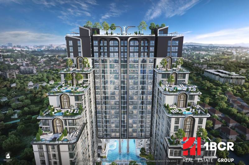 Apartment construction in Pattaya with rooftop terraces and pools amidst greenery.