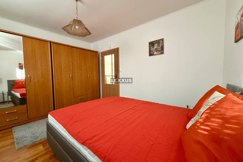 Bedroom with a wooden wardrobe, red bed, and ceiling light in a family house.