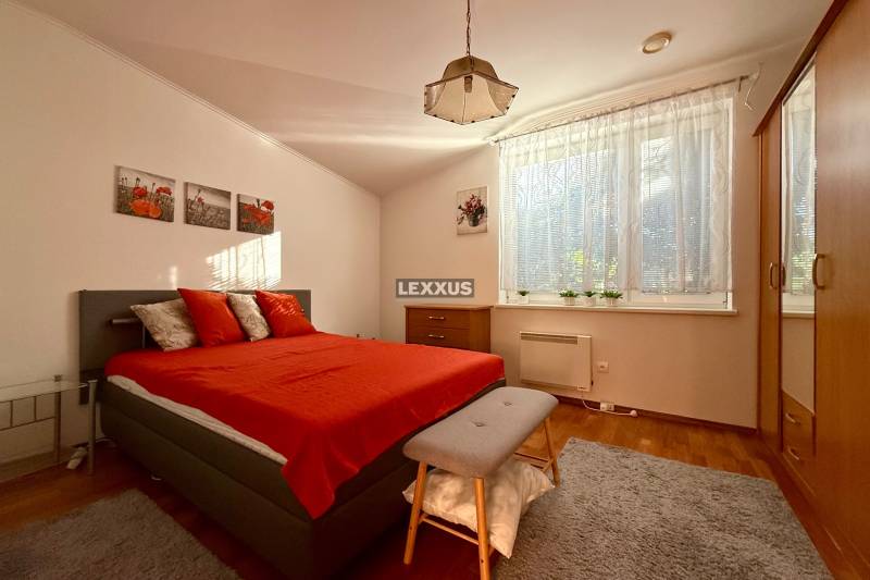Bedroom in a family house with a red bed, wardrobe, and large window.