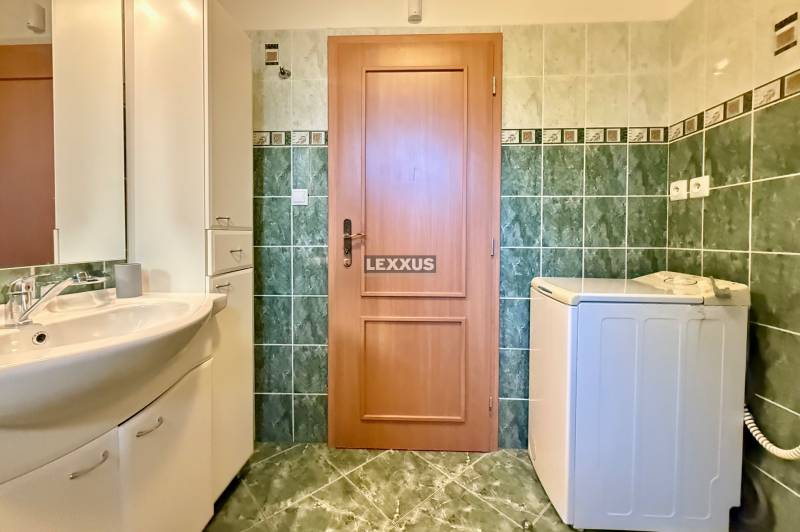Bathroom with a washing machine, sink, and tiles in a family house.