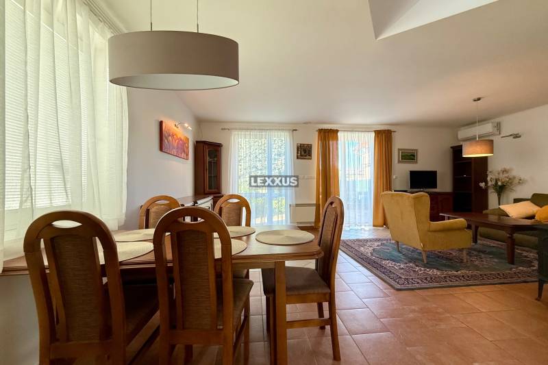 Dining room and living room in a family house with wooden furniture and a large carpet.