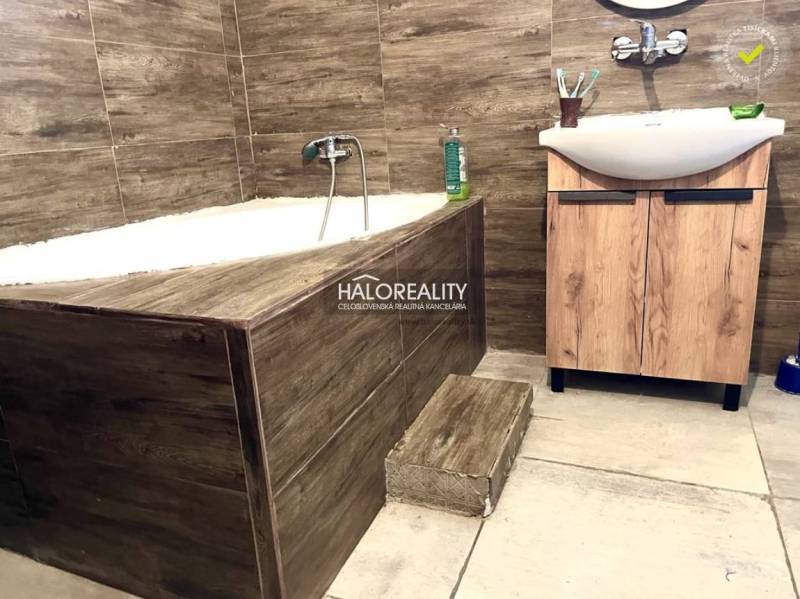 A bathroom in a family house with a built-in bathtub and a wooden sink.
