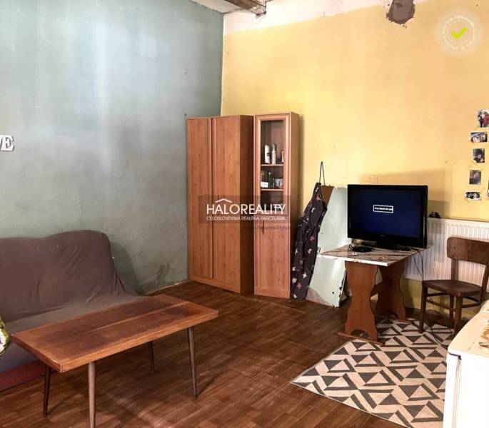 Living room with a sofa, wardrobe, and television in a family house, simple furnishings.