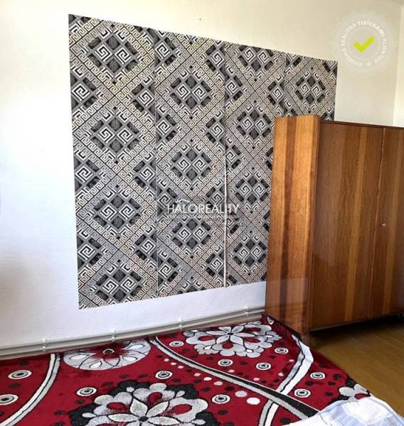 Black and white geometric wallpaper, wooden cabinet, and floral carpet in a family house.