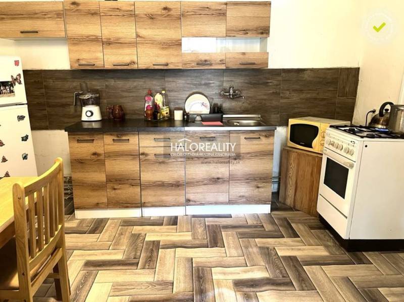A kitchen in a family house with wooden cabinets, a stove, and a refrigerator.