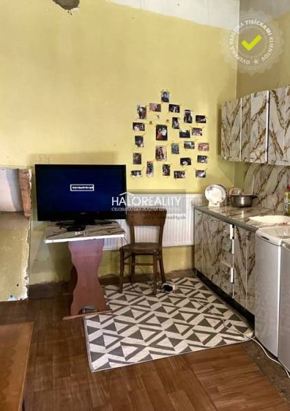 A kitchen in a family house with a television, photos on the wall, and a stove.
