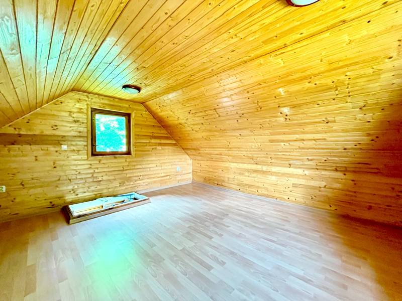 Wooden interior cladding of the attic with a window in a family house.