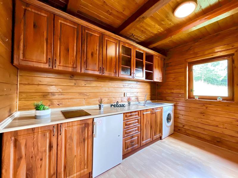 A wooden kitchen in a family house with wooden cabinets and a view from the window.