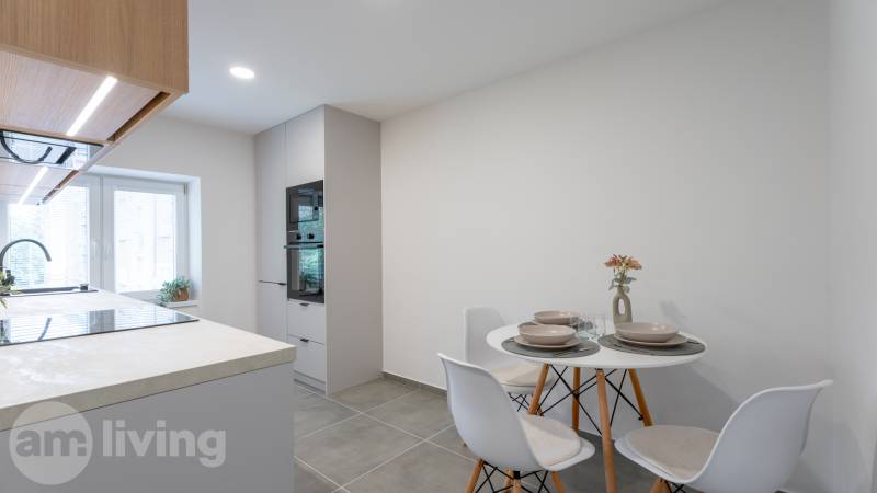 A kitchen in a studio apartment with modern equipment and a small dining table.