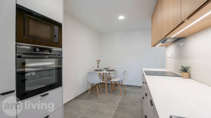 A kitchen in a studio apartment with a table, chairs, and a built-in oven.
