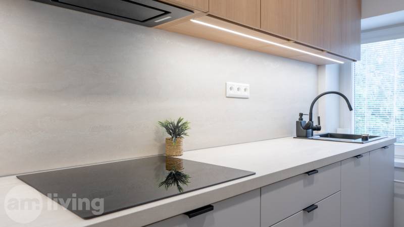 A kitchen in a studio apartment with a built-in cooktop and sink, with a view from the window.