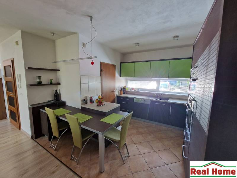 A kitchen in a family house with a dining table and green details.