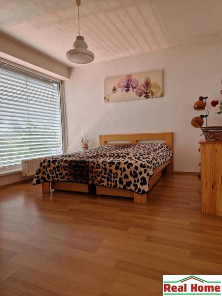 Bedroom in a family house with a large window, bed, and picture on the wall.