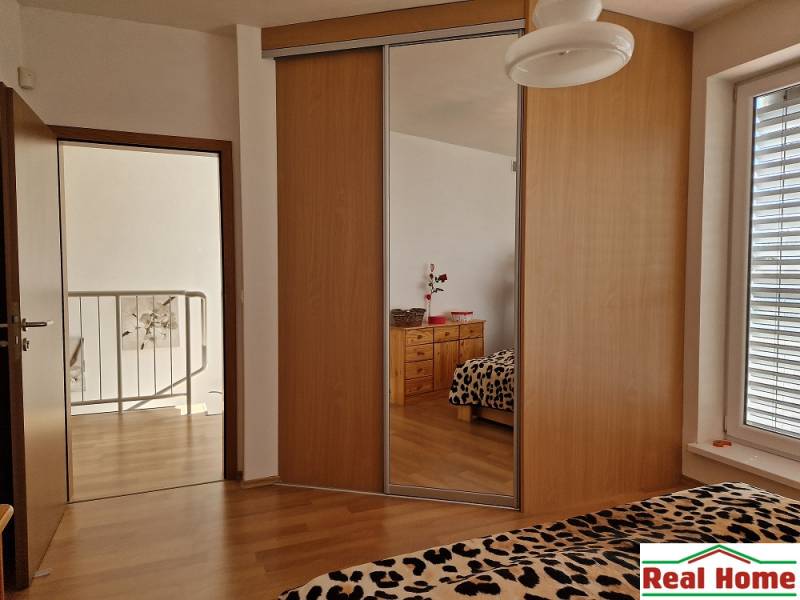 Interior of a family house with a built-in wardrobe, a mirror, and leopard patterns on the bed.