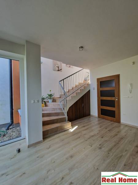 A bright hallway with a wooden staircase and railing in a family house.