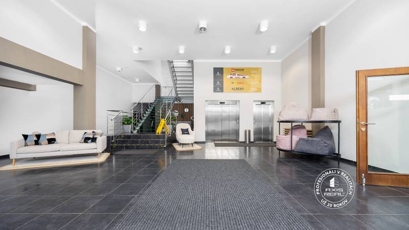 Reception with a sofa, elevators, and staircase in commercial premises.