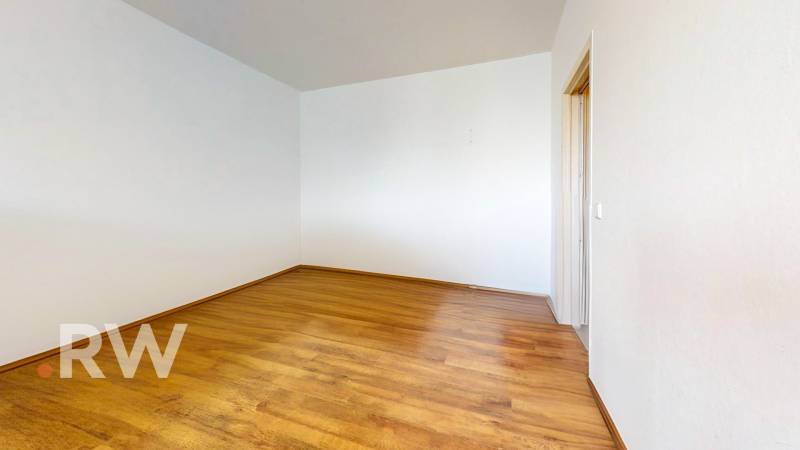 Empty room with wooden flooring in a studio apartment. White walls, simple design.