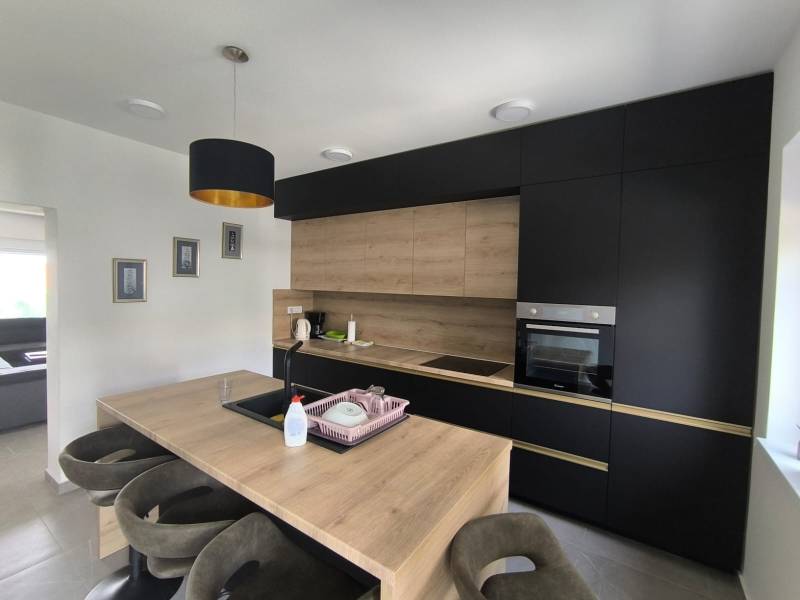 The kitchen in a 4-room apartment with dark cabinets and wooden details.