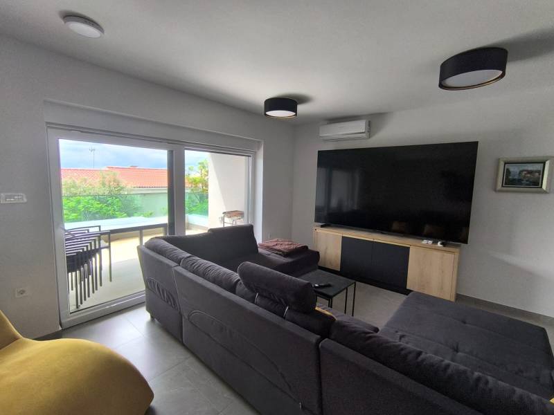 Living room in a 4-room apartment with a sofa, TV, and a view of the terrace.