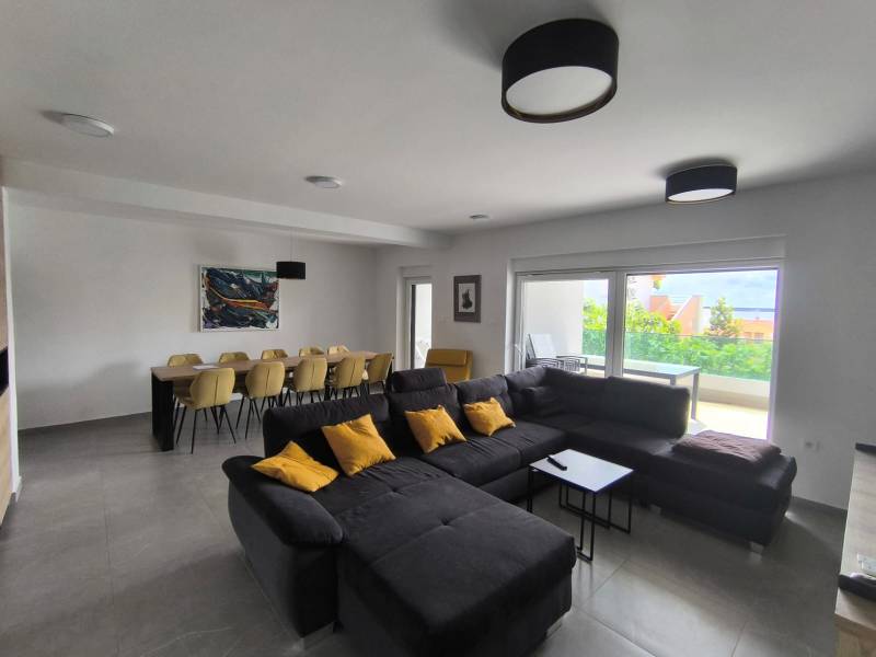 Living room in a 4-room apartment with a large sofa, dining table, and a view of the terrace.