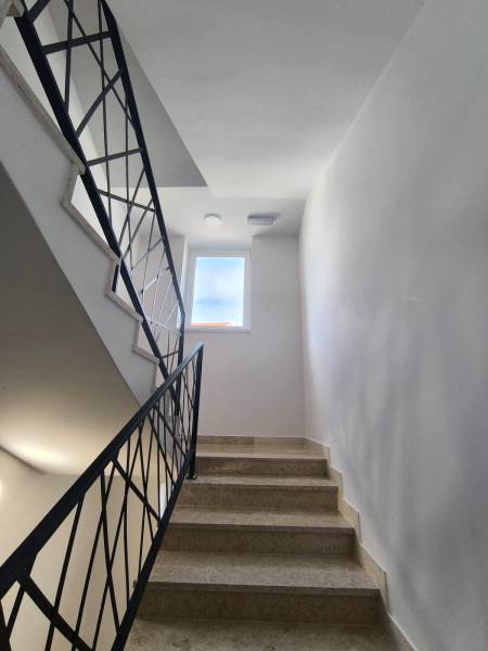 A staircase in a 4-room apartment with a window and elegant railings.