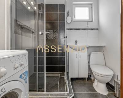 Bathroom in a family house with a washing machine, shower, and toilet.