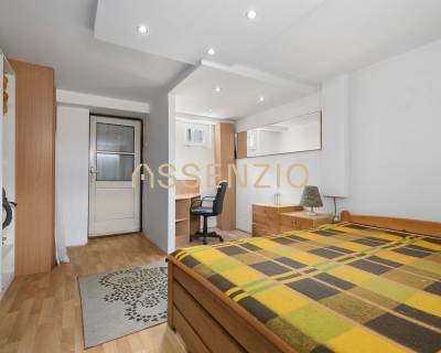 Bedroom in a family house with a wooden bed, desk, and wardrobes.