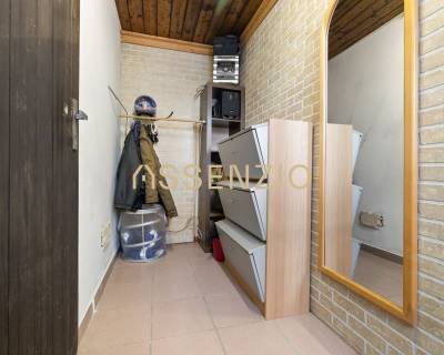 A narrow hallway with a coat rack, mirror, and storage space in a family house.