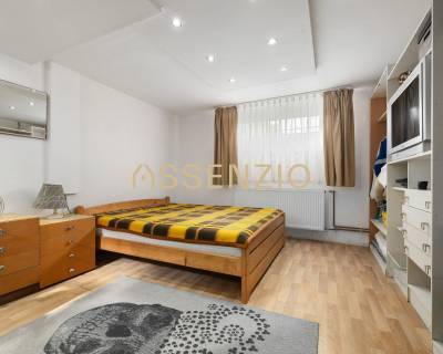 Bright bedroom with wooden flooring, bed, dresser, and carpet in a family house.