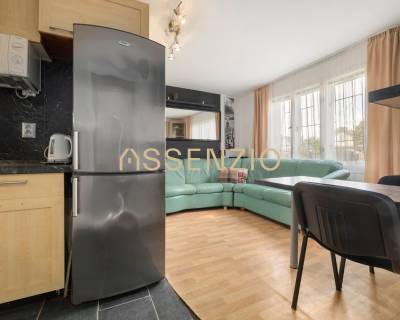 A kitchen with a refrigerator and a dining area next to the living room in a family house.