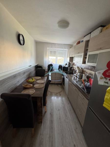 A kitchen in a 3-room apartment with a dining table, wooden floor, and a window.
