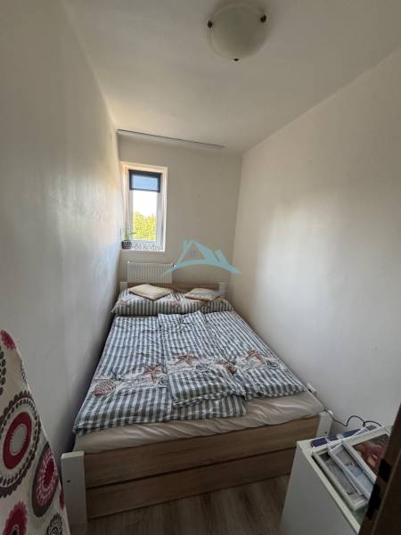 A small bedroom with a bed in a three-room apartment, simple furnishings and a white interior.