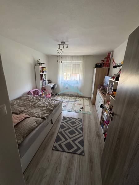 Children's room with a bed and a window in a 3-room apartment, light wooden floor.