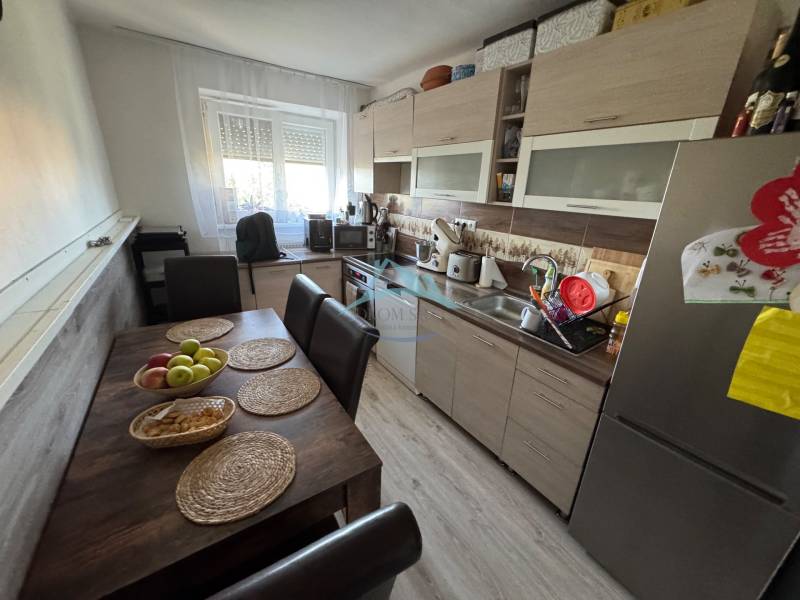 A kitchen in a 3-room apartment with a table, chairs, and modern equipment in pleasant lighting.