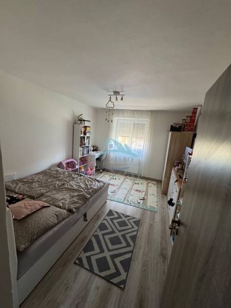 Bedroom with a bed and a bookshelf in a 3-room apartment, light flooring, decorative carpet.