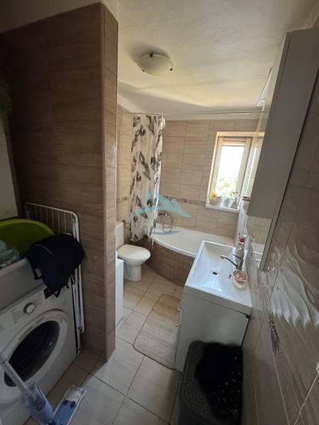 Bathroom with a washing machine, bathtub, and sink in a 3-room apartment.