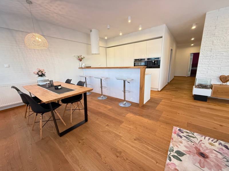 Dining area with a wooden table and a kitchen bar counter in a 4-room apartment.