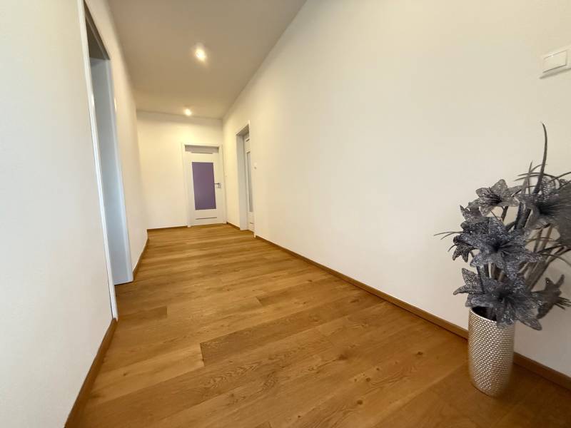 A hallway in a 4-room apartment with light walls and wooden flooring.