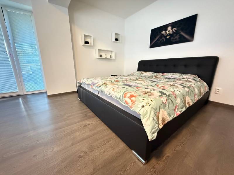 Bedroom with a bed and a painting in a 4-room apartment, wooden floor, large window.